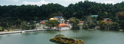 The sacred Temple of the Tooth in Kandy against a backdrop of green hills.